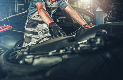 Midsection of mechanic repairing car at garage