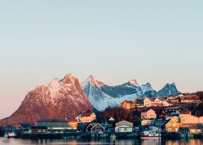 Panoramic shot of buildings by mountains against clear sky