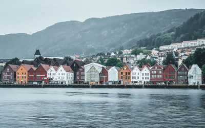 Buildings by sea against mountain