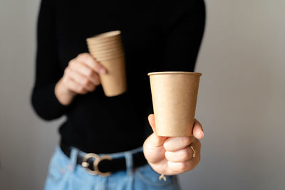 Woman in black shirt holding paper cup of craft paper. zero waste material. ecology concept.