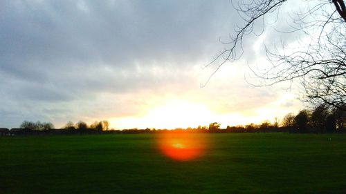 Scenic view of grassy field against sky at sunset