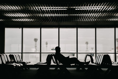 Silhouette of man sitting at airport