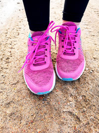 Low section of woman standing on pink land