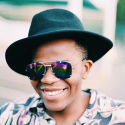 Close-up portrait of smiling young woman wearing sunglasses