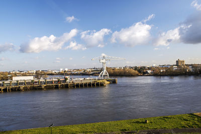 Bridge over river by buildings against sky