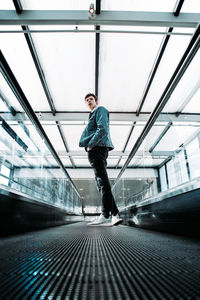 Side view of man standing on moving walkway