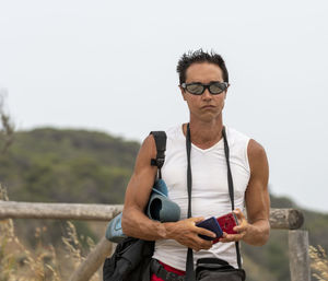 Young man wearing sunglasses while standing against trees