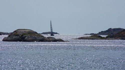 Sea by rocks against clear sky