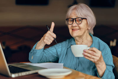 Portrait of senior woman gesturing at cafe