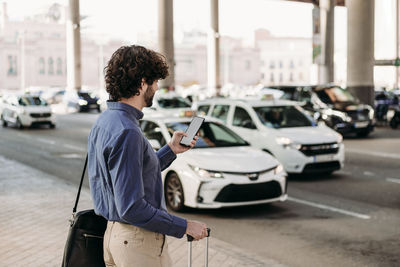 Businessman using smart phone standing at footpath