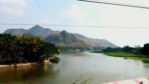 Scenic view of river by mountains against sky