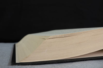 Close-up of open book on table against black background