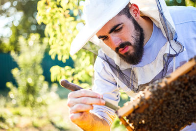 Beekeeper working by plants on field during sunny day