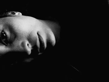 Close-up portrait of young woman over black background