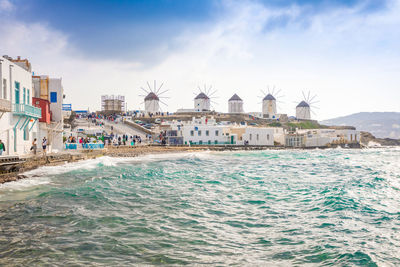 Buildings by sea against blue sky