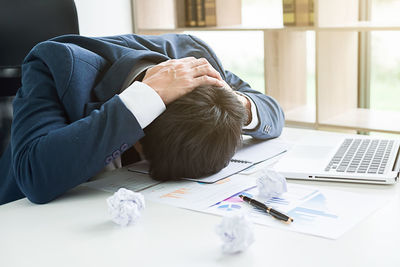 Stressed businessman resting head on desk in office