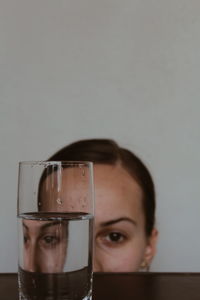 Close-up of drinking glass on table with woman in background
