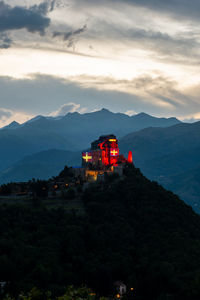 High angle view of illuminated building by mountains against sky