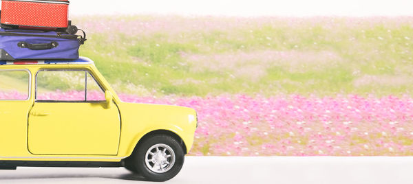 Close-up of yellow vintage car with luggage against field
