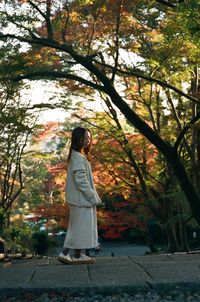 Woman standing by tree during autumn