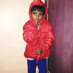 Portrait of cute boy standing against red wall