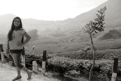 Young woman standing on landscape against mountains