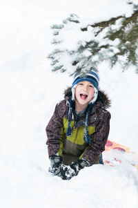 Portrait of boy screaming while playing in snow