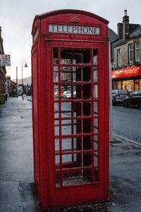 Red telephone booth on sidewalk in city