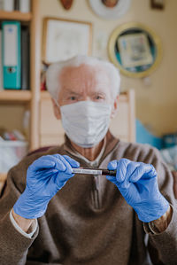 Portrait of senior man wearing protective gloves at home