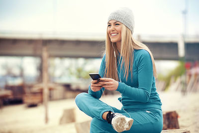 Smiling young woman using mobile phone outdoors