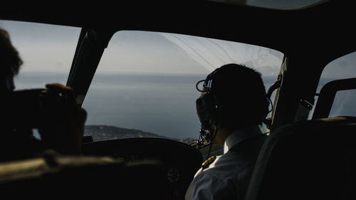 Rear view of pilot sitting in cockpit of airplane