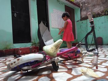 Girl with umbrella standing outside house 