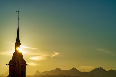 The sun rises behind the tower of the heiliggeistkirche in bern, switzerland