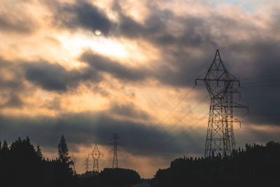 Low angle view of silhouette electricity pylon against sky during sunset