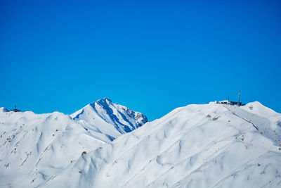 Low angle view of snowcapped mountains against clear blue sky