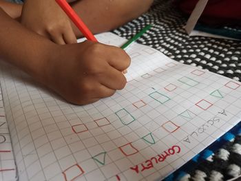 High angle view of child writing in book