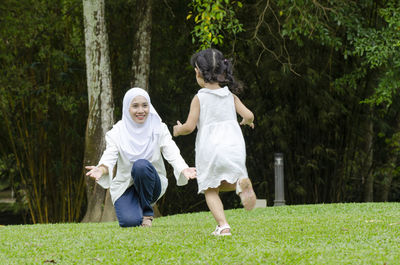 Full length of a girl standing on grass against trees