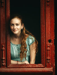 Portrait of beautiful young woman looking through doorway