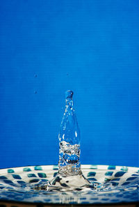 Close-up of water splashing on table against blue background