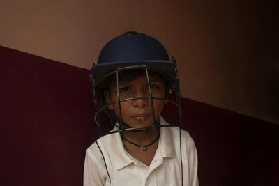 Portrait of boy wearing sports helmet against wall