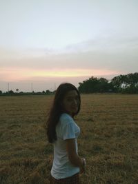 Full length of woman standing on field against sky during sunset