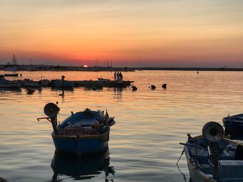 Boats moored in sea against sky during sunset