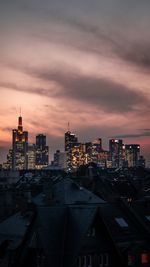 Modern buildings in city against sky at sunset