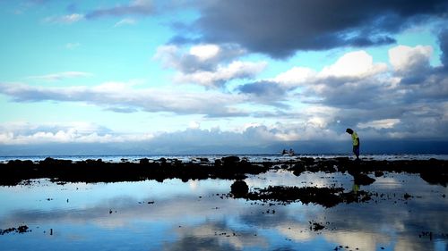 Silhouette man standing by sea against sky