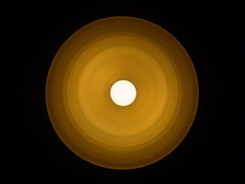 Low angle view of illuminated pendant light against black background