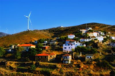 Houses by buildings against clear blue sky
