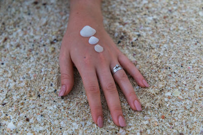 Close-up of woman hand with pebble stones on sand