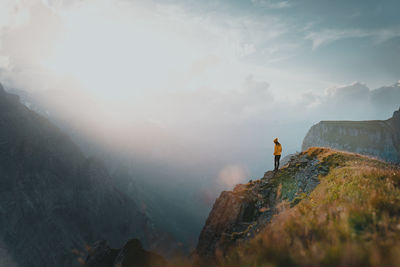 Full length of woman standing by cliff against sky