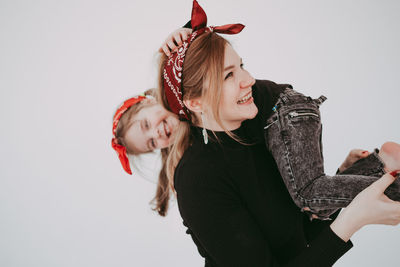 Happy woman carrying daughter against white background