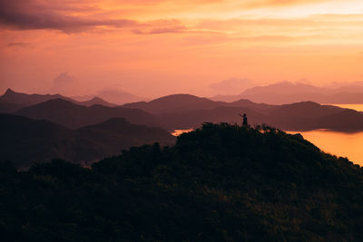 Scenic view of silhouette mountains against orange sky